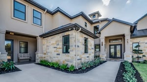 A sand-colored home with stone accents, surrounded by beautiful landscape and greenery, creating an inviting and harmonious exterior.