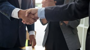 Two business professionals shaking hands in a firm and confident gesture, symbolizing a successful and professional agreement.