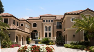 Luxury multi-story home with palm trees, flowers, and a water fountain for landscaping